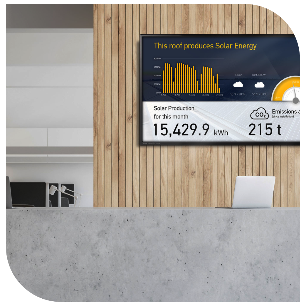 A reception desk with a screen mounted on the wall above it. The screen displays the amount of solar energy the school produces